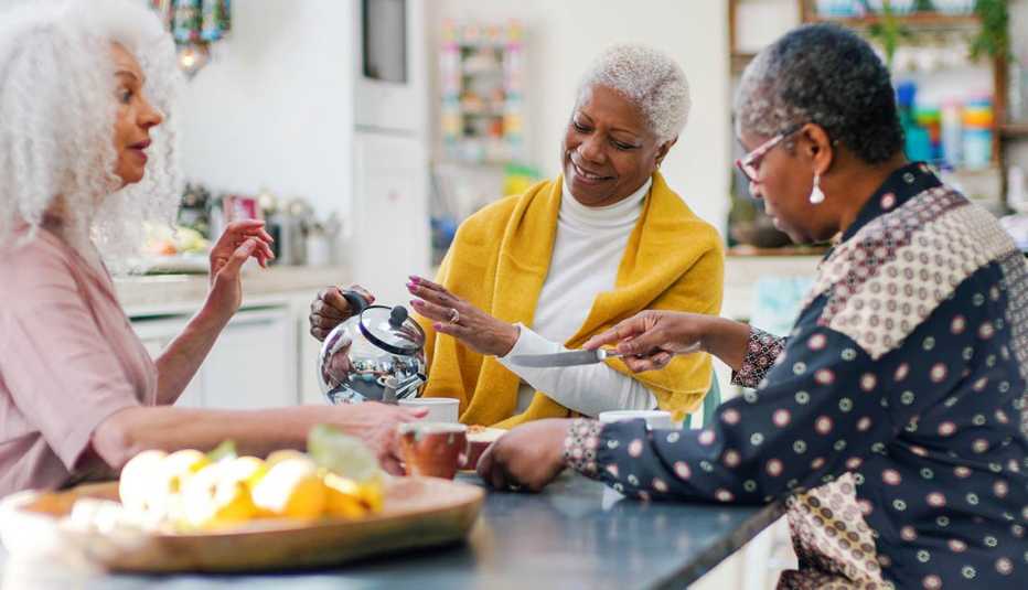 mature women sitting at a kitcher table drinking tea together