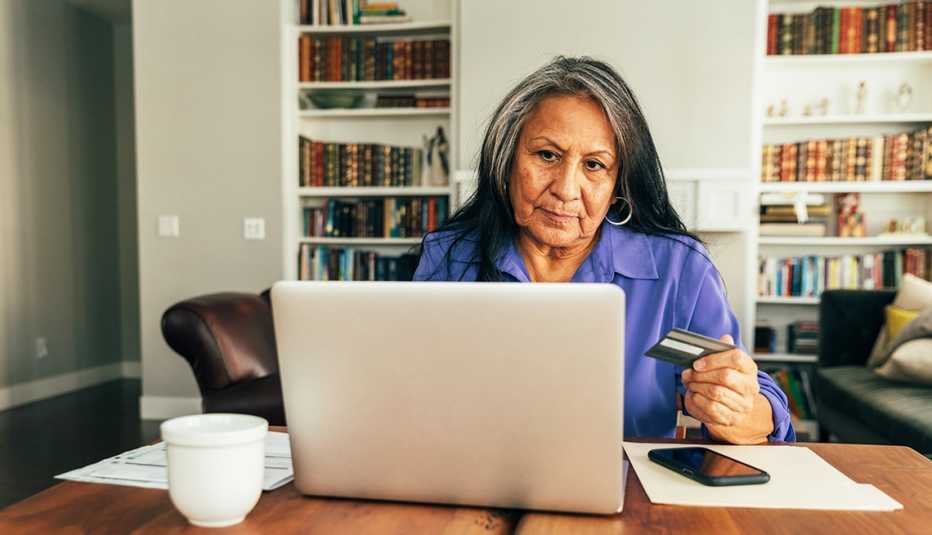 A senior adult woman sits at the dining table paying bills and banking using her mobile laptop. She is using his credit card for his online banking, paying of bills, and shopping. A senior adult woman sits at the dining table paying bills and banking using her mobile laptop. She is using his credit card for his online banking, paying of bills, and shopping.