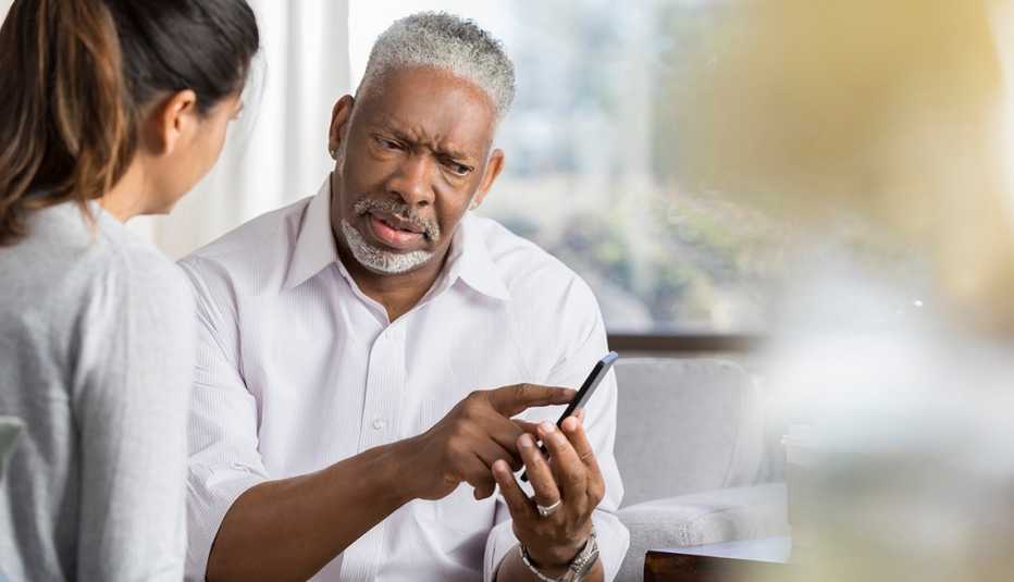 Confused man shows something on a smartphone to female friend.