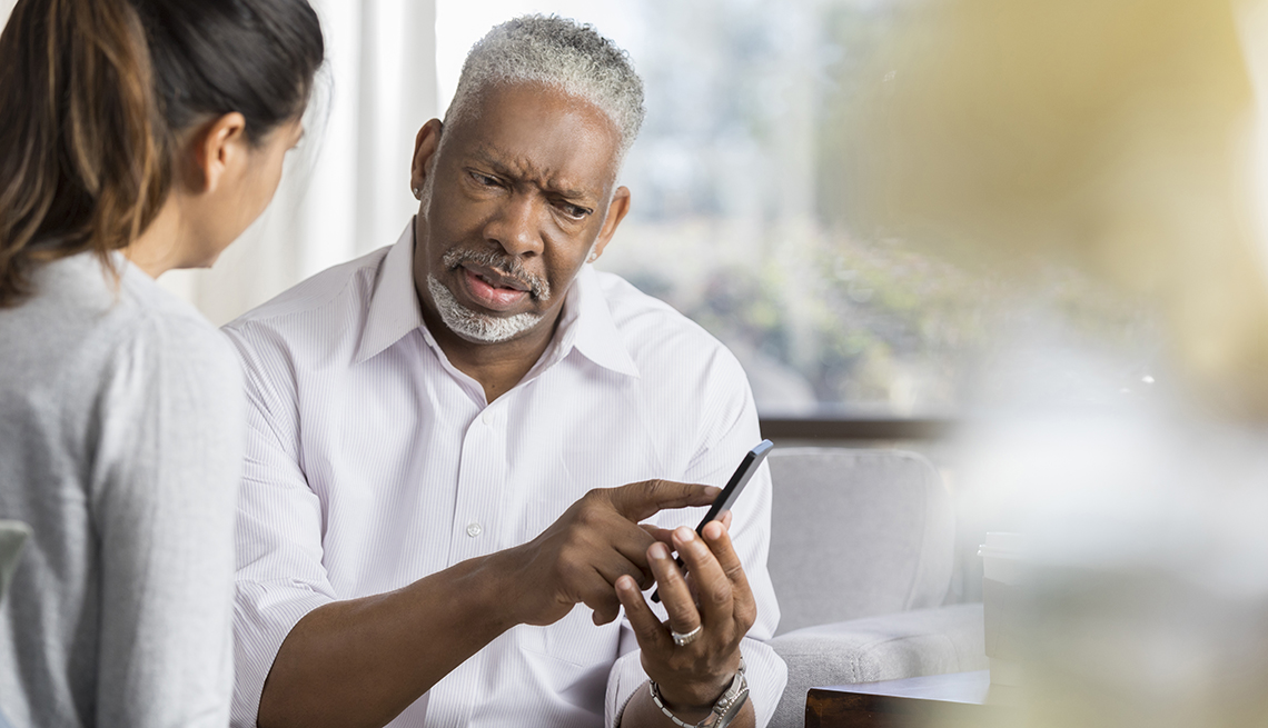 Confused man shows something on a smartphone to female friend.
