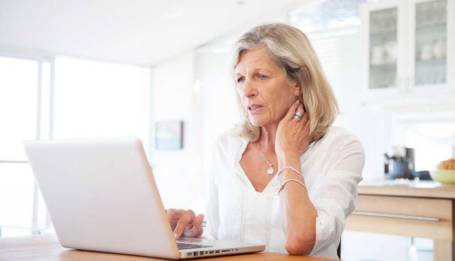Senior woman, aged 64, working on laptop computer in kitchen