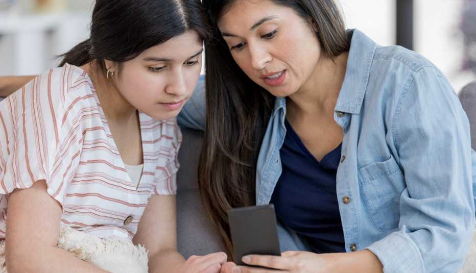 mother and her teenage daughter looking at phone together mother and her teenage daughter looking at phone together