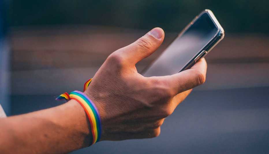 A man holding a phone with a rainbow bracelet