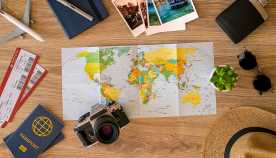 Travel stuff on desktop: map, sun glasses, camera, tickets, passport etc.