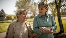 older woman and mother with locked arms walking and talking outside