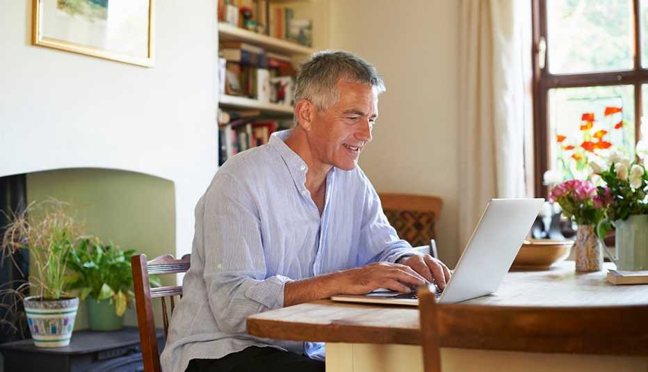 A man sitting at a table and using a laptop