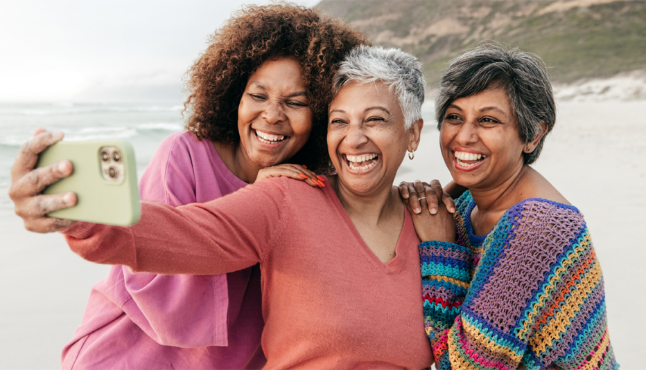 Three women taking a selfie on the beach and laughing together
