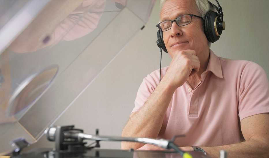 A man with headphones on listening to a record