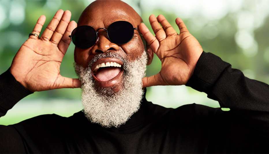 A man smiling with his hands up beside his head