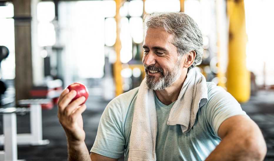 A man eating an apple in a gym