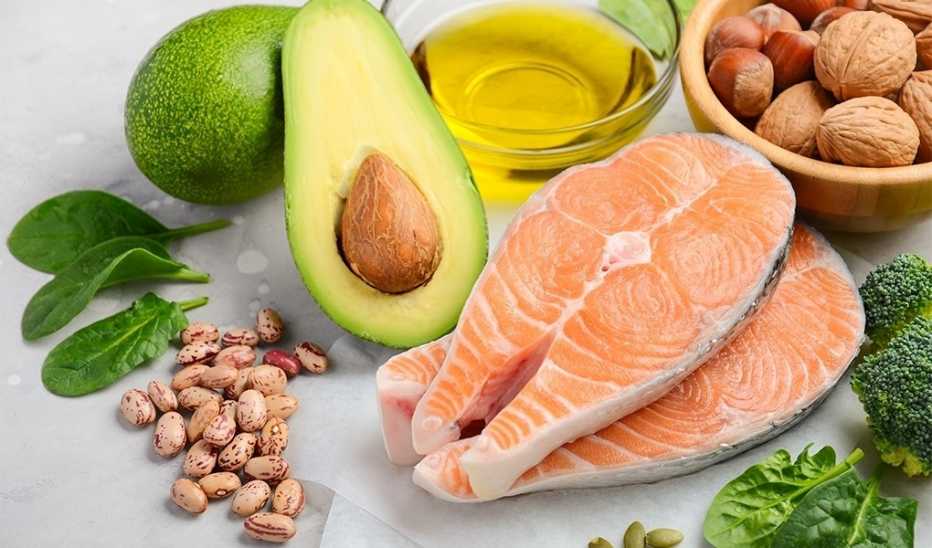 A close-up view of salmon, beans, avocado, olive oil, spinach, broccoli and mixed nuts
