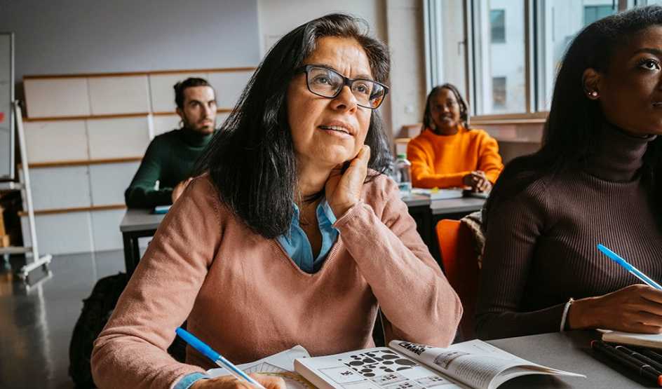 A woman taking notes in an adult education class with other students