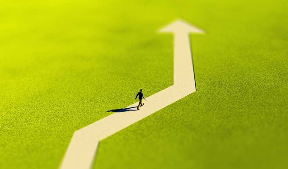 A man walking on an arrow-shaped path surrounded by grass