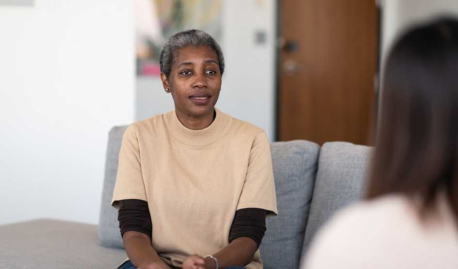 A woman sitting on a couch while talking to a therapist