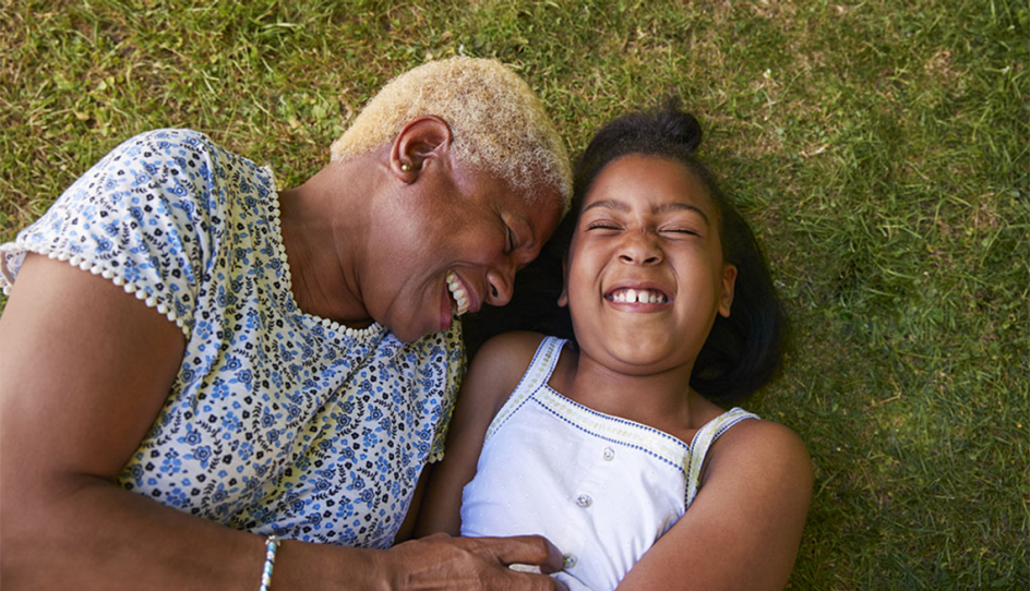A woman and girl lying in the grass and laughing